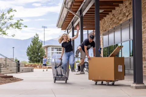 Two people at move in walk down the sidewalk jump and pose